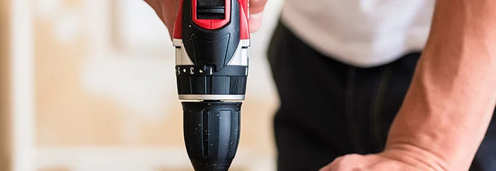 Person bohrt mit Bohrmaschine in Holz